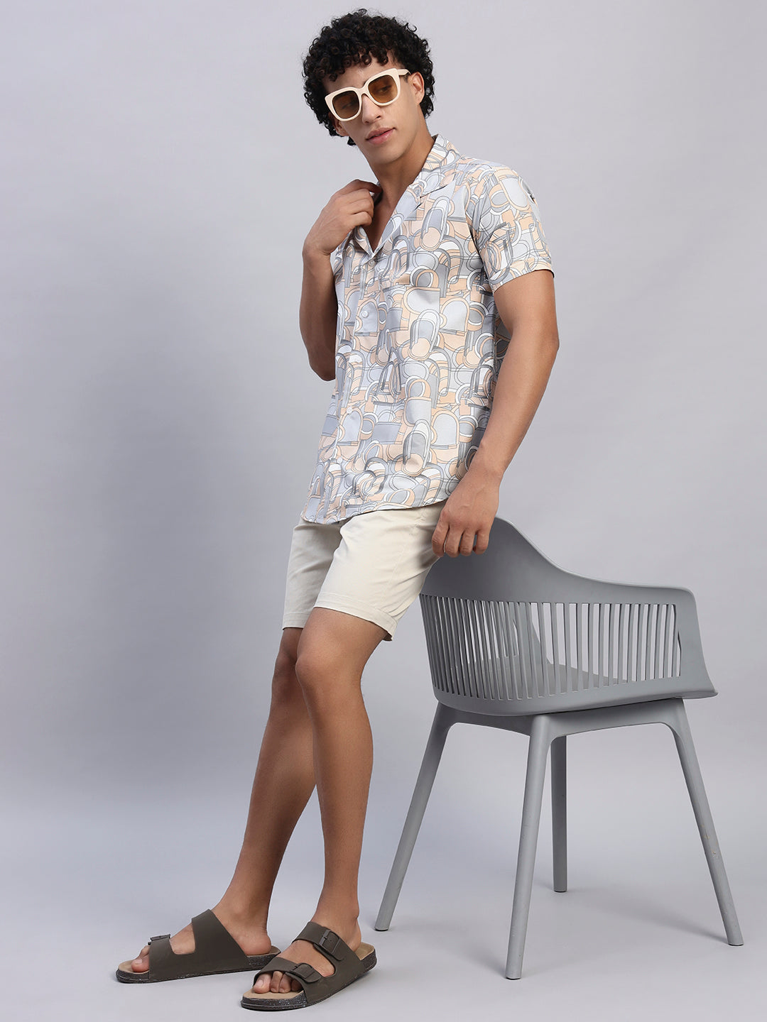 Full look: Men’s beige and pastel abstract print shirt paired with beige shorts, sunglasses, and sandals — SMOKHEAD casual resort summer outfit